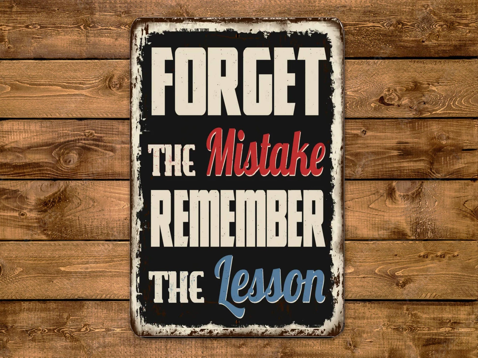 a sign on a wooden wall that reads forget the mistake remember the lesson