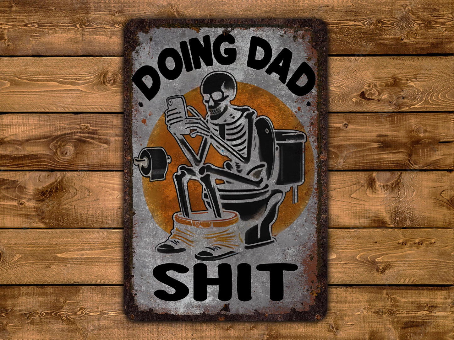A metal sign with a skeleton sitting on a toilet and holding a phone, with the text "DOING DAD SHIT" written above it.