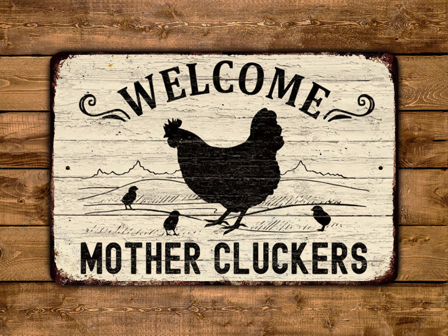 A sign with the text "WELCOME MOTHER CLUCKERS" and a silhouette of a rooster, along with three smaller rooster silhouettes, is displayed on a wooden background.