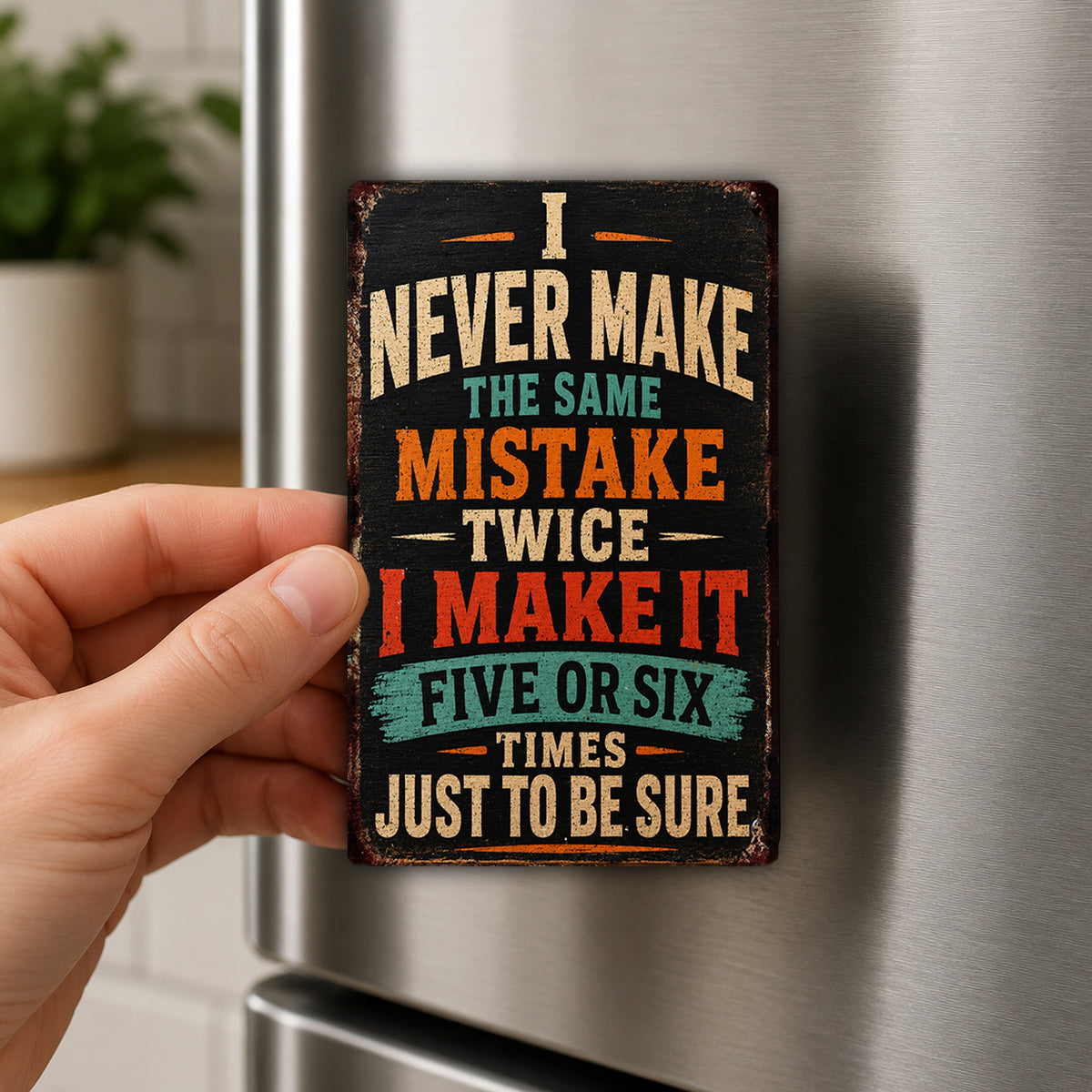 A person's hand holding a sign with the text "I NEVER MAKE THE SAME MISTAKE TWICE I MAKE IT FIVE OR SIX TIMES JUST TO BE SURE" on it.