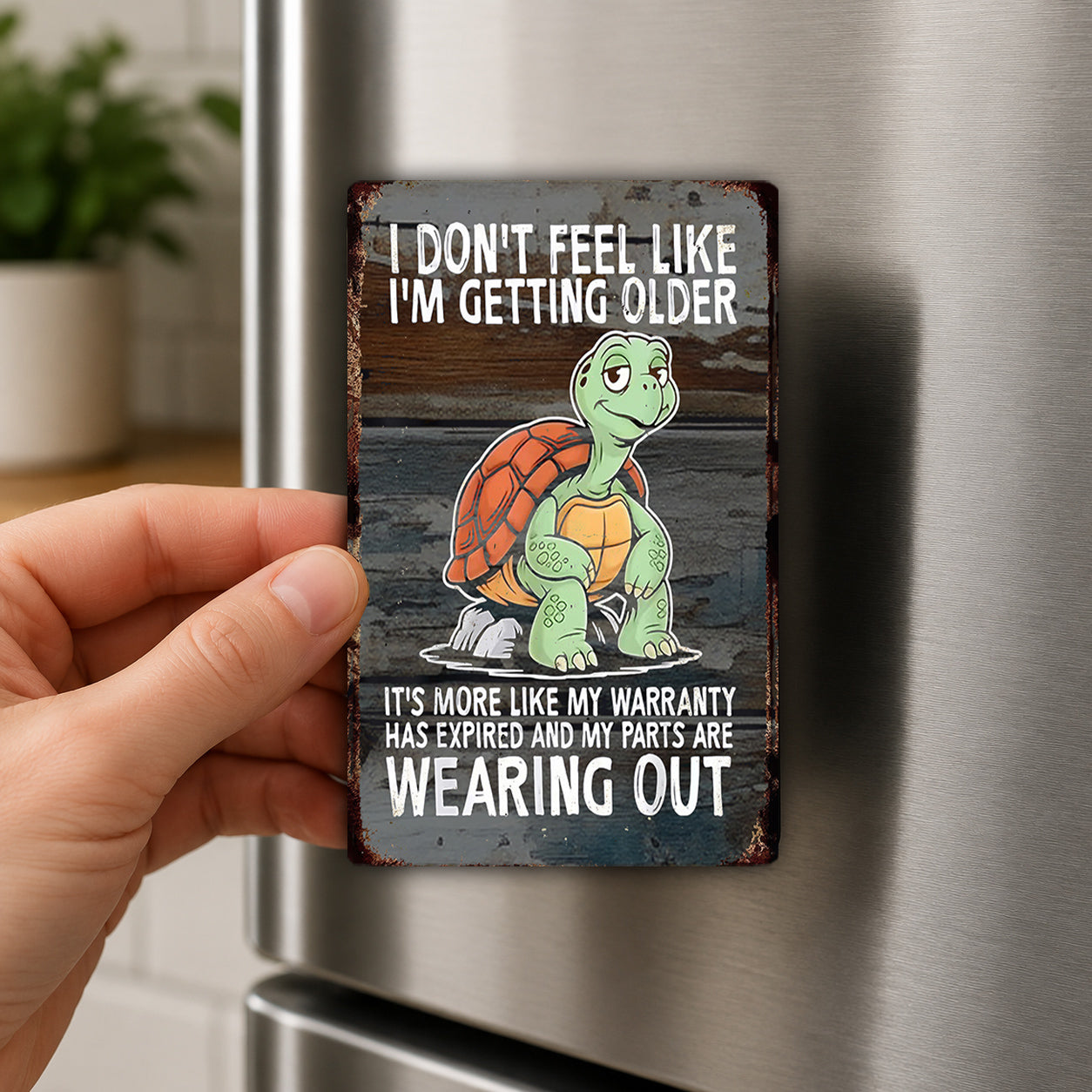 A person's hand holding a metal sign with a cartoon turtle and text on it.