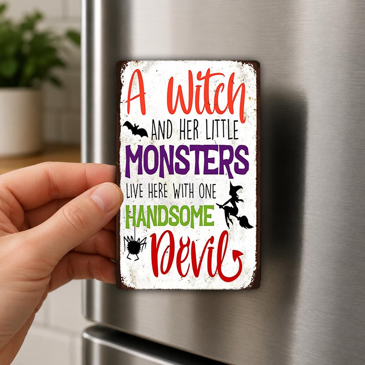 A person's hand holding a small metal sign with text on it.