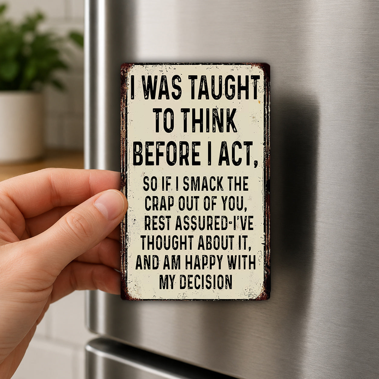A person's hand holding a small, rectangular sign with a humorous message on it.