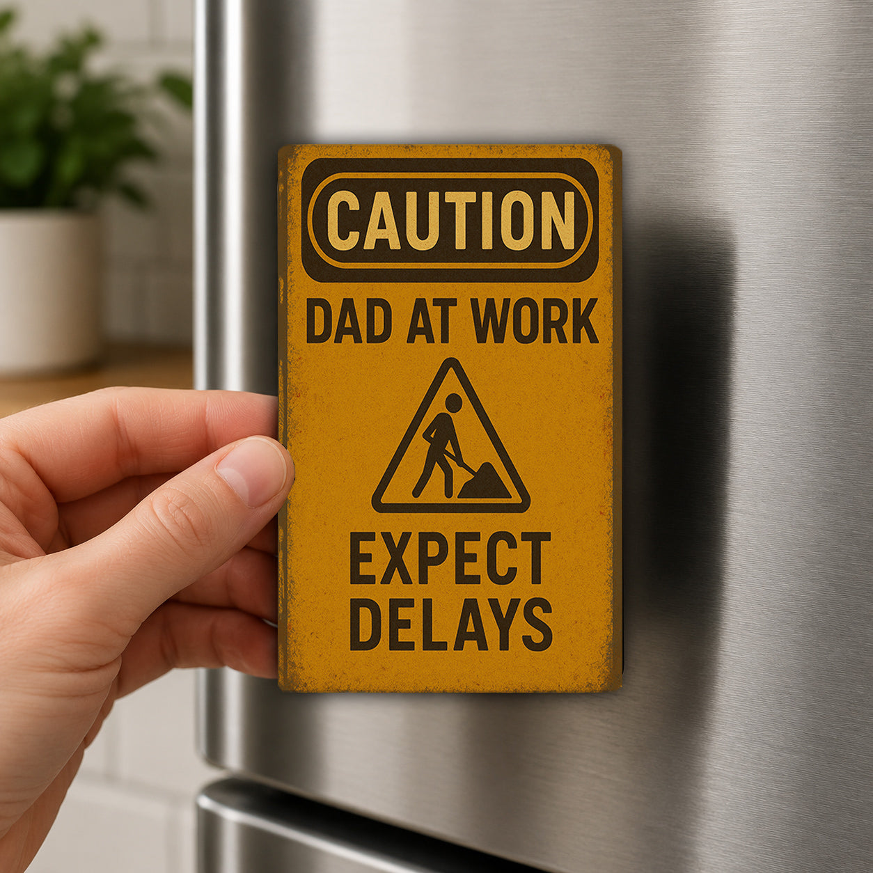 A person's hand is holding a yellow caution sign attached to a refrigerator.