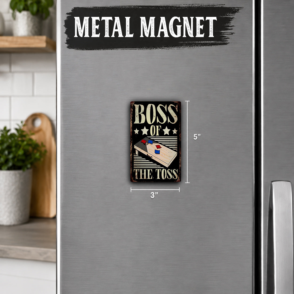 a small metal magnet with the text "BOSS OF THE TOSS" on it, placed on a refrigerator.
