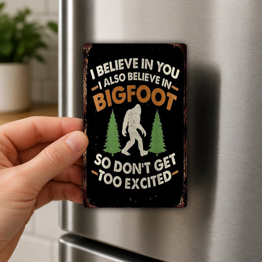 A person's hand is holding a metal sign with a humorous text and a silhouette of a Sasquatch.