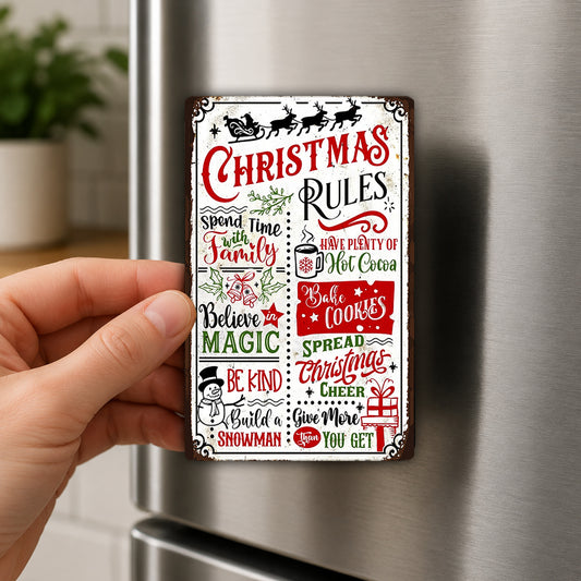 A person's hand is holding a Christmas-themed metal sign with various holiday-related rules and phrases.