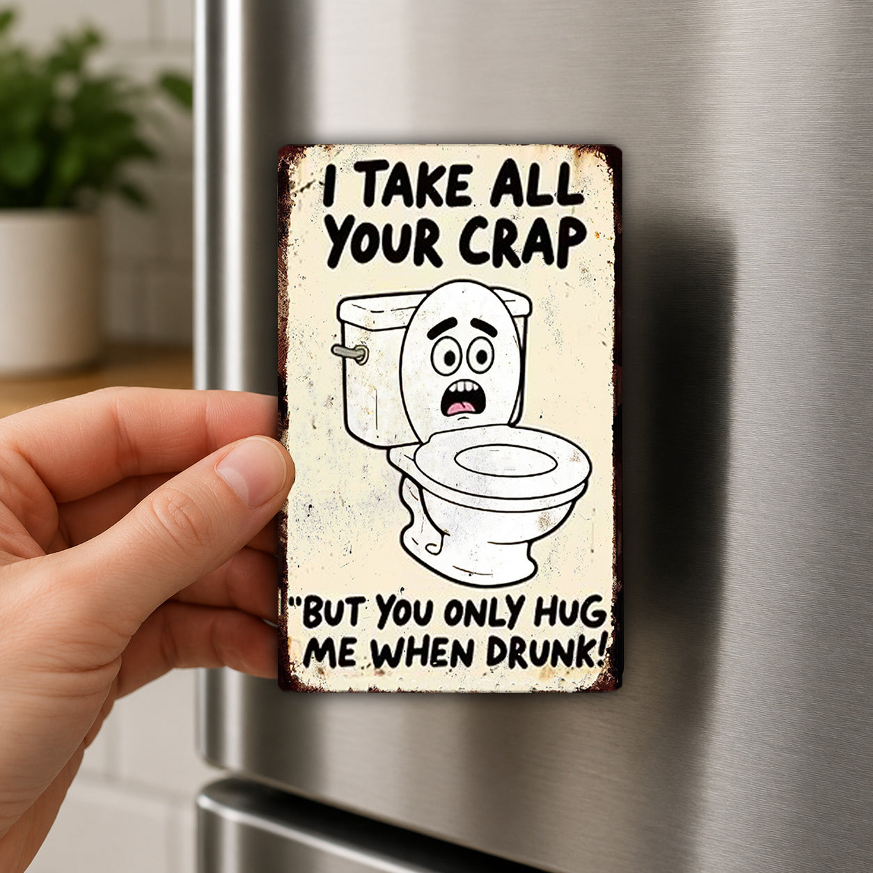 A person's hand is holding a metal sign with a cartoon image of a toilet and text that reads "I TAKE ALL YOUR CRAP 'BUT YOU ONLY HUG ME WHEN DRUNK!"